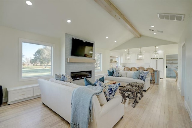 living room featuring a fireplace, vaulted ceiling with beams, and light hardwood / wood-style flooring