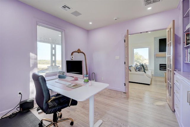 office with a large fireplace and light hardwood / wood-style floors