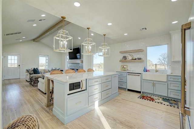 kitchen with sink, vaulted ceiling with beams, light hardwood / wood-style floors, white appliances, and a kitchen bar