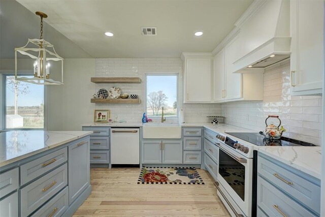 kitchen featuring white appliances, premium range hood, sink, light hardwood / wood-style flooring, and white cabinetry