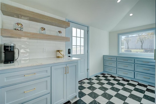 interior space featuring plenty of natural light, backsplash, and vaulted ceiling