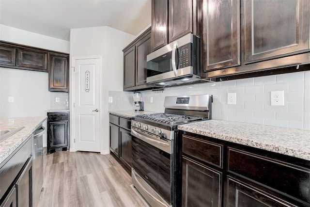 kitchen featuring light stone countertops, light wood-type flooring, appliances with stainless steel finishes, and dark brown cabinets