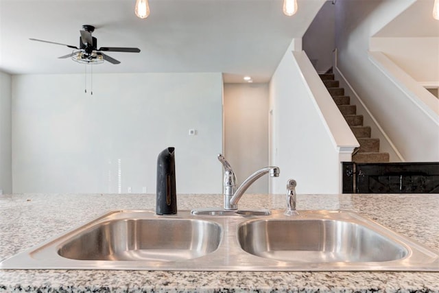 kitchen with ceiling fan, sink, and light stone counters