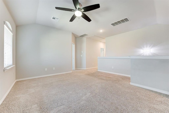 spare room featuring ceiling fan, light colored carpet, a healthy amount of sunlight, and vaulted ceiling