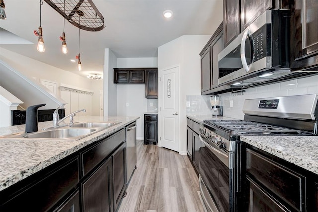 kitchen featuring appliances with stainless steel finishes, decorative light fixtures, decorative backsplash, sink, and light hardwood / wood-style floors