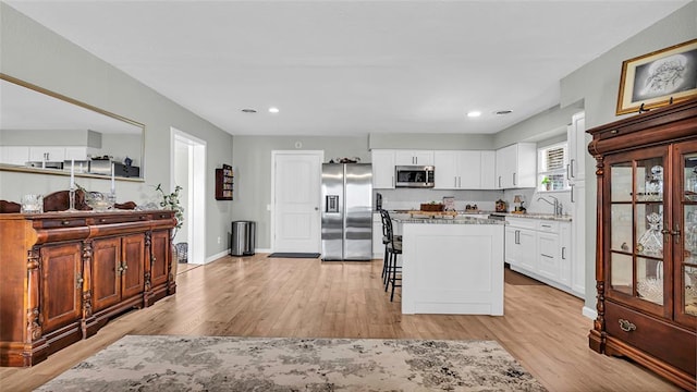 kitchen with a breakfast bar area, a center island, stainless steel appliances, and light wood-type flooring