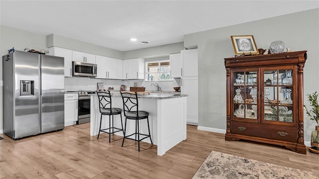 kitchen featuring white cabinets, a kitchen island, light wood-type flooring, and appliances with stainless steel finishes