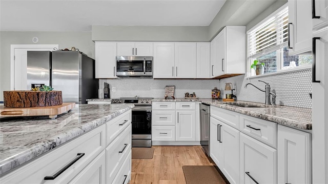 kitchen with tasteful backsplash, white cabinetry, sink, and stainless steel appliances