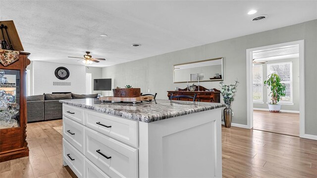 kitchen featuring light wood-type flooring, white cabinetry, a kitchen island, and ceiling fan