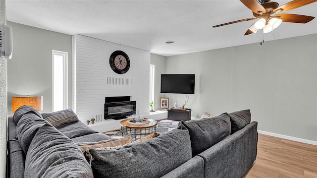 living room featuring a fireplace, ceiling fan, and light hardwood / wood-style flooring