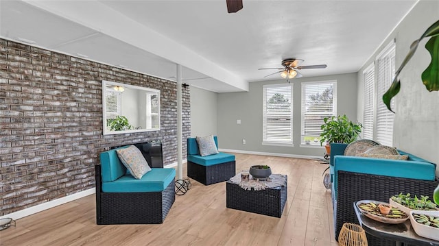 sitting room with hardwood / wood-style flooring, ceiling fan, and brick wall