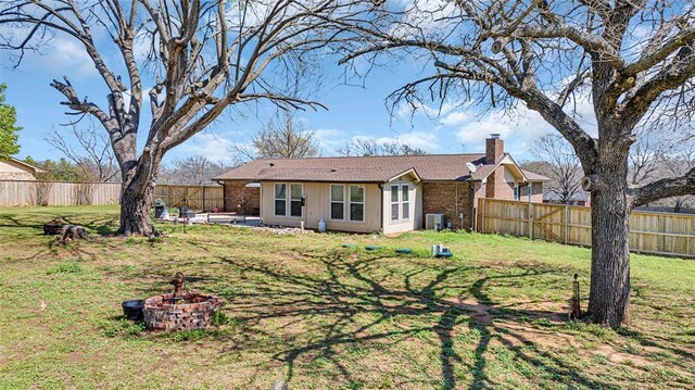 back of property featuring a yard, cooling unit, and a fire pit