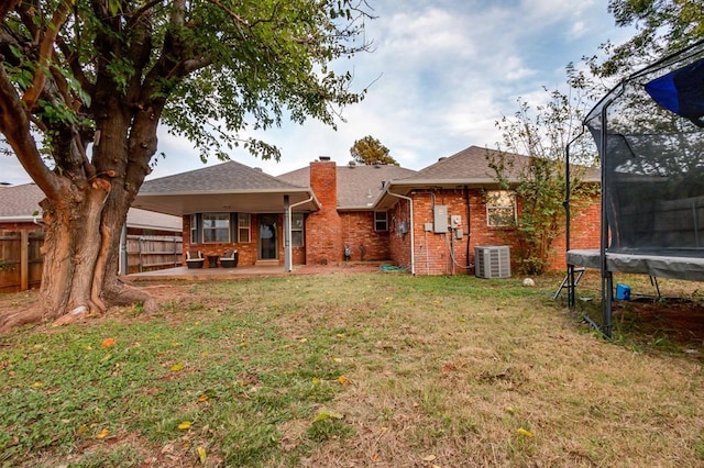 back of property with cooling unit, a patio, a yard, and a trampoline