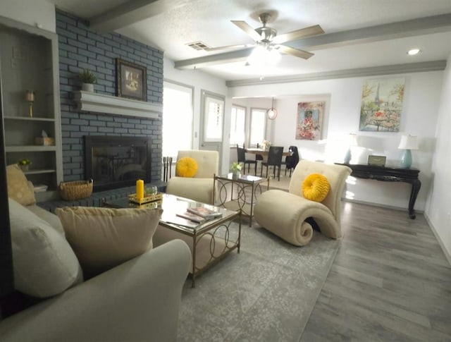 living room featuring wood-type flooring, a brick fireplace, and ceiling fan