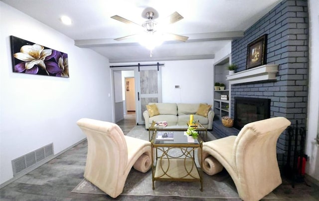 living room featuring built in features, beamed ceiling, ceiling fan, a barn door, and a brick fireplace