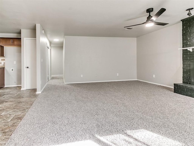 unfurnished living room with light colored carpet, a brick fireplace, and ceiling fan