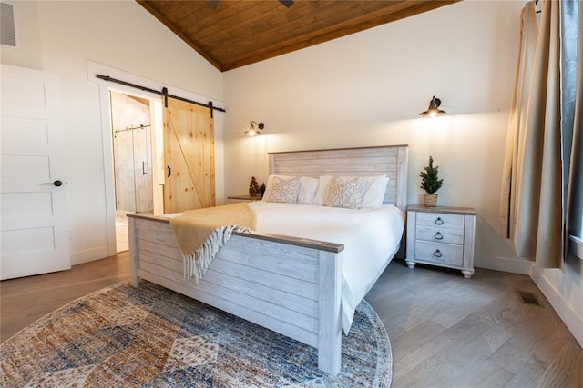 bedroom with lofted ceiling, ensuite bathroom, dark hardwood / wood-style floors, a barn door, and wood ceiling