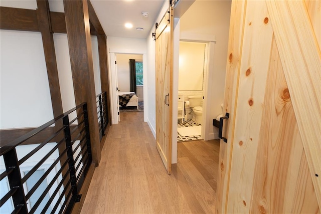 hall featuring a barn door and light hardwood / wood-style flooring