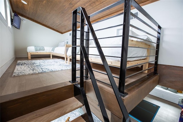 staircase featuring hardwood / wood-style floors, wood ceiling, crown molding, and vaulted ceiling