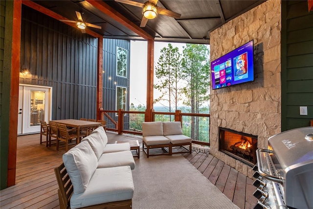 sunroom featuring an outdoor stone fireplace, ceiling fan, and wooden ceiling