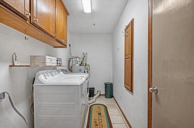 laundry area with washing machine and clothes dryer, cabinets, light tile patterned floors, and water heater