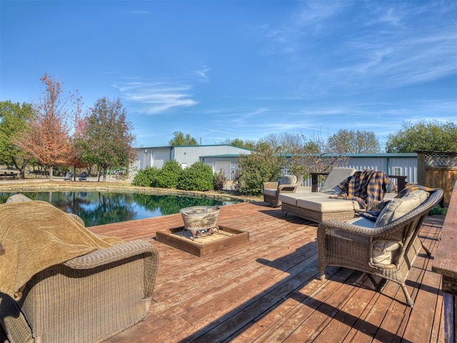 wooden terrace featuring a water view and an outdoor fire pit