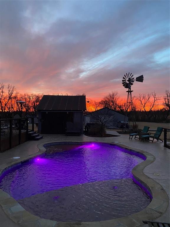 pool at dusk with a patio area