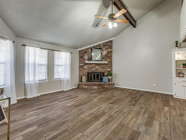 unfurnished living room featuring vaulted ceiling with beams, a brick fireplace, and light wood-type flooring