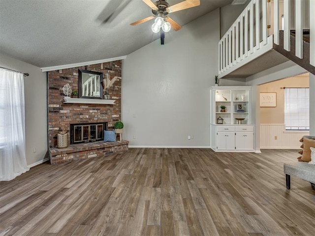 unfurnished living room featuring a textured ceiling, vaulted ceiling, ceiling fan, hardwood / wood-style flooring, and a fireplace