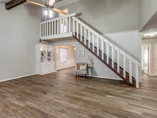 unfurnished living room featuring beam ceiling, hardwood / wood-style flooring, high vaulted ceiling, and ceiling fan