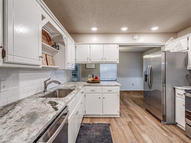 kitchen with decorative backsplash, light wood-type flooring, stainless steel appliances, sink, and white cabinetry