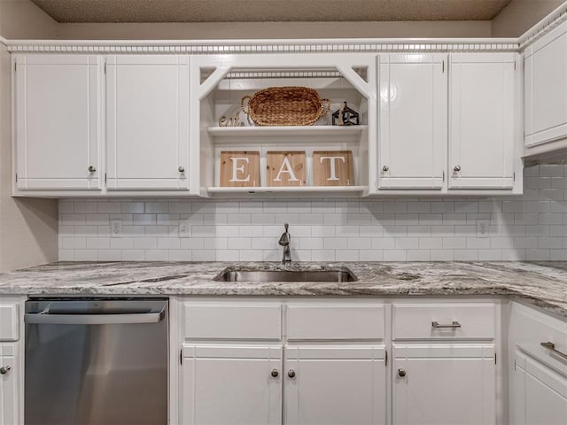 kitchen featuring white cabinets, stainless steel dishwasher, light stone countertops, and sink