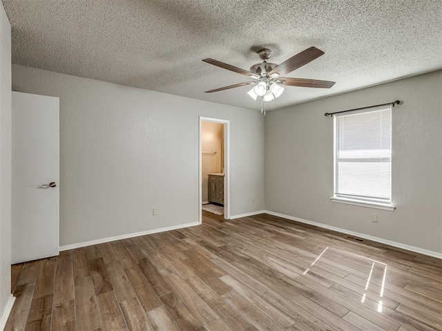 empty room with a textured ceiling, light hardwood / wood-style floors, and ceiling fan