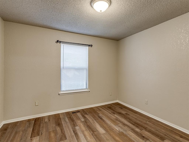 unfurnished room featuring wood-type flooring and a textured ceiling