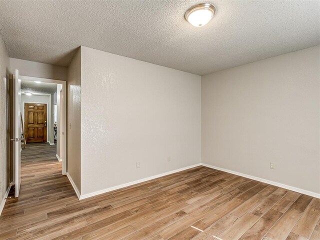 empty room featuring light wood-type flooring and a textured ceiling