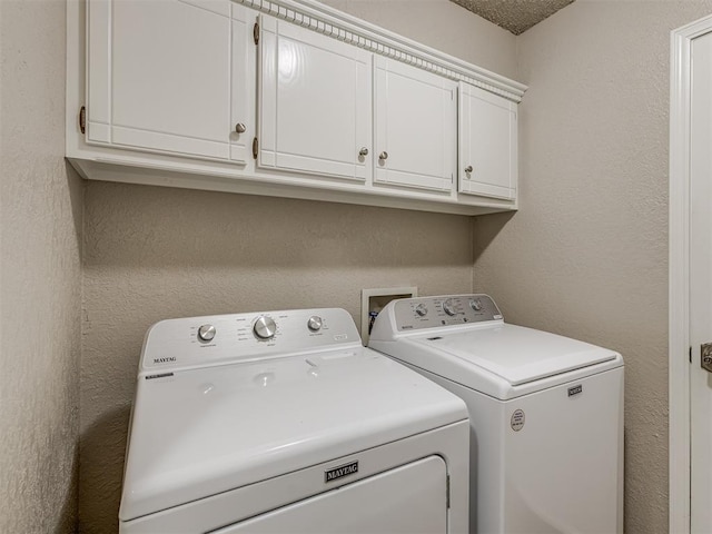 laundry area with cabinets, a textured ceiling, and washing machine and dryer