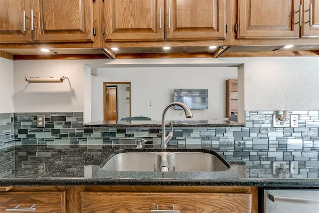 kitchen featuring dishwasher, sink, backsplash, and dark stone countertops