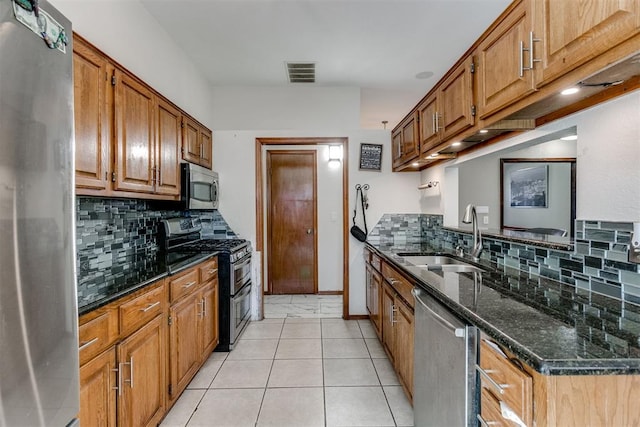 kitchen with backsplash, stainless steel appliances, dark stone counters, and sink