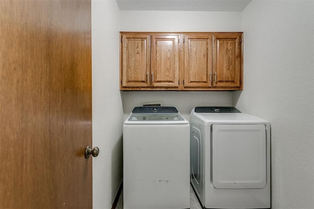 laundry room featuring cabinets, independent washer and dryer, and a textured ceiling