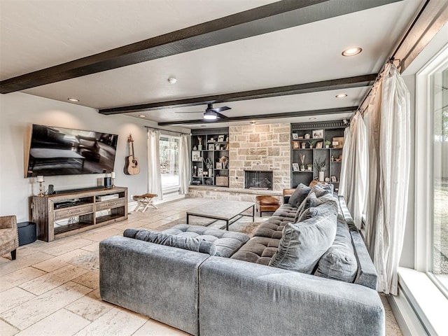 living room featuring built in features, beam ceiling, a stone fireplace, and ceiling fan