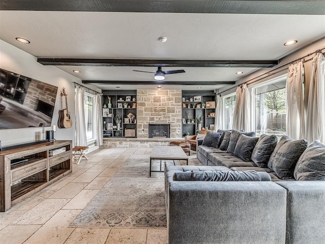 living room featuring ceiling fan, a stone fireplace, built in features, beamed ceiling, and a textured ceiling