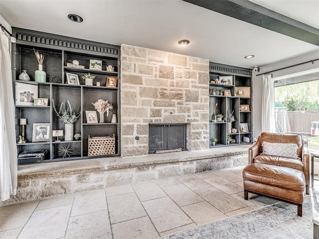 sitting room with built in features and a stone fireplace