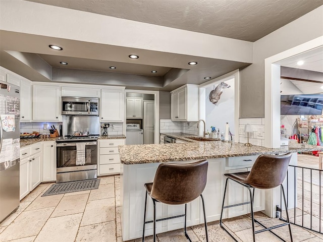 kitchen with white cabinetry, kitchen peninsula, stainless steel appliances, and a breakfast bar area