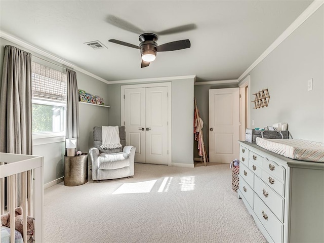 carpeted bedroom featuring ceiling fan, a crib, ornamental molding, and a closet