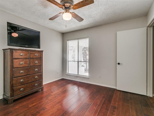 unfurnished bedroom with ceiling fan, dark hardwood / wood-style flooring, and a textured ceiling