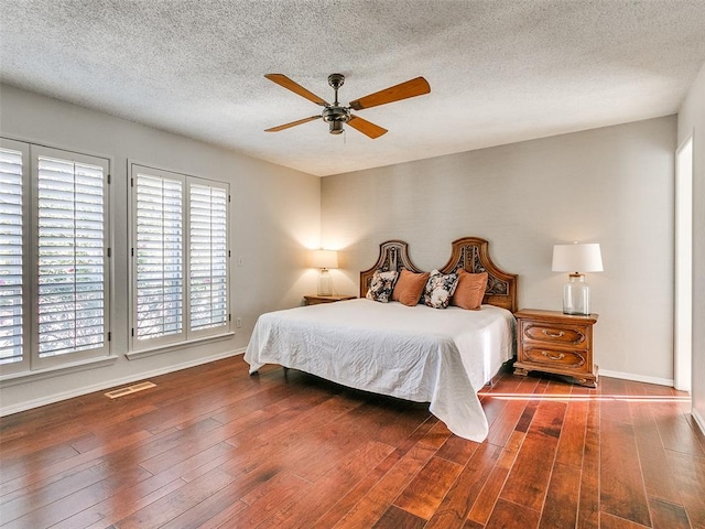 bedroom with a textured ceiling, ceiling fan, and dark wood-type flooring