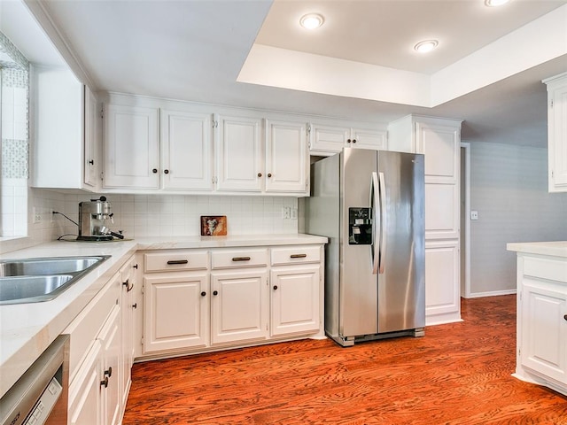 kitchen with decorative backsplash, stainless steel fridge, light wood-type flooring, dishwashing machine, and white cabinetry