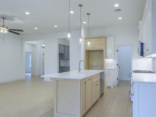 kitchen with a center island with sink, sink, ceiling fan, appliances with stainless steel finishes, and decorative light fixtures