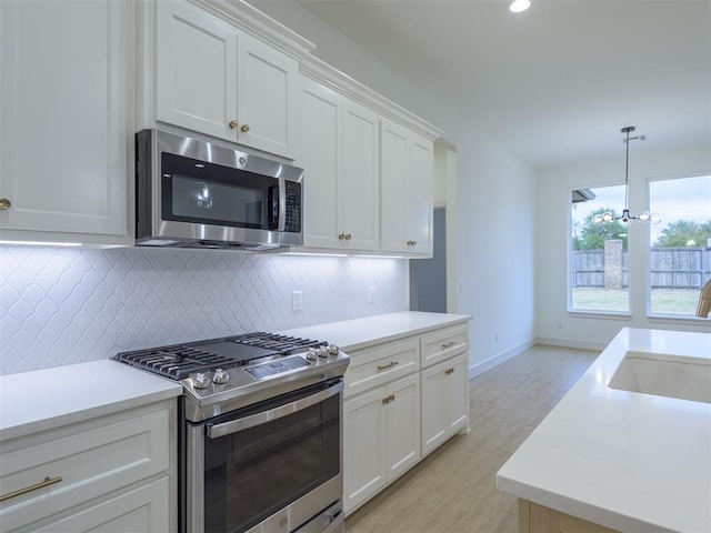 kitchen with appliances with stainless steel finishes, light hardwood / wood-style flooring, white cabinetry, and sink