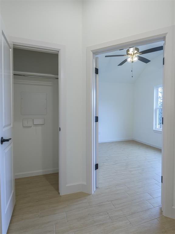 hall with vaulted ceiling and light wood-type flooring